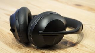 Ett par svarta Bose Noise Cancelling Headphones 700 ligger på ett träfärgat bord.