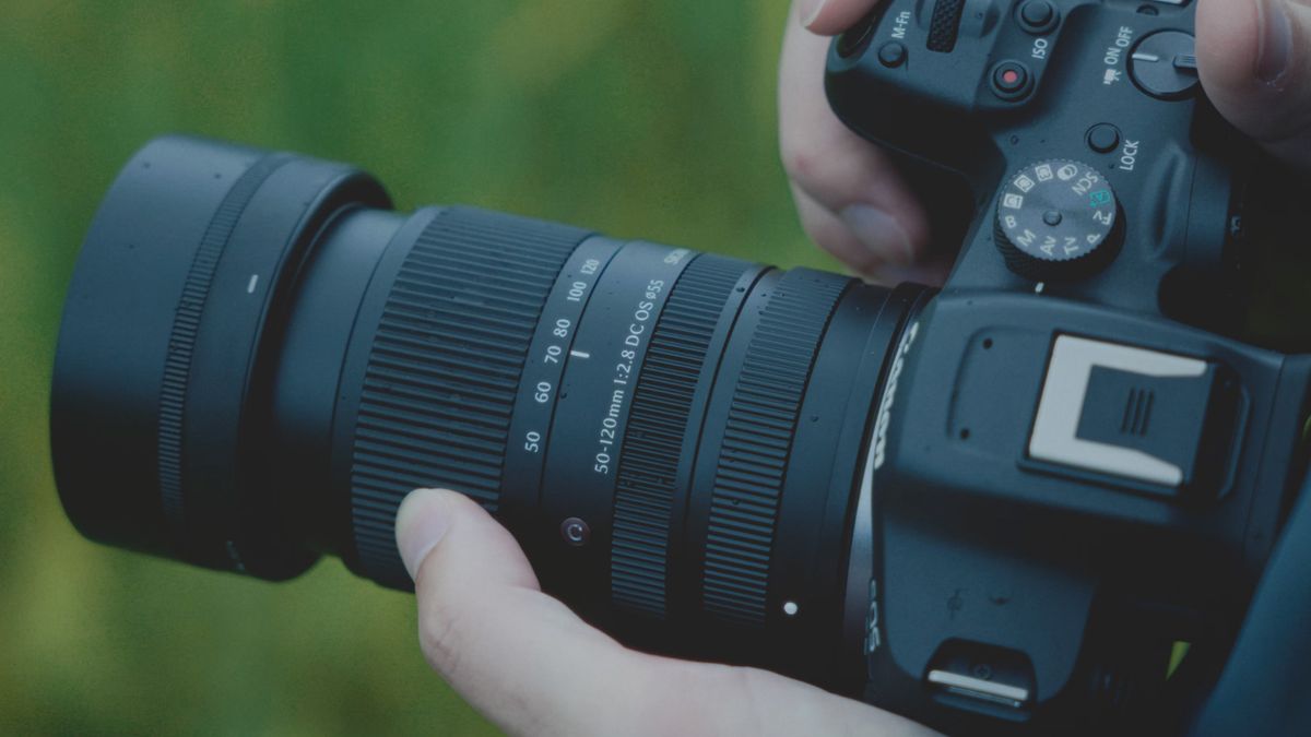 Sigma 50-120mm F2.8 DC OS Contemporary lens attached to a Canon camera, held by a photographer outdoors