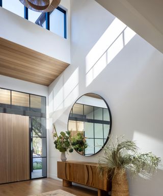 doubleheight entryway with wooden floor and round mirror