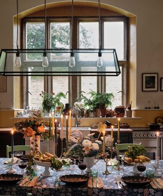 fall tablescape with glowing taper candles and a floral tablecloth