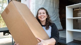 A woman carries a bed in a box