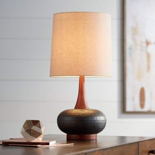 Round dark wooden bulbous lamp with tall cream shade styles on a wooden side table with wooden abstract mini ornament