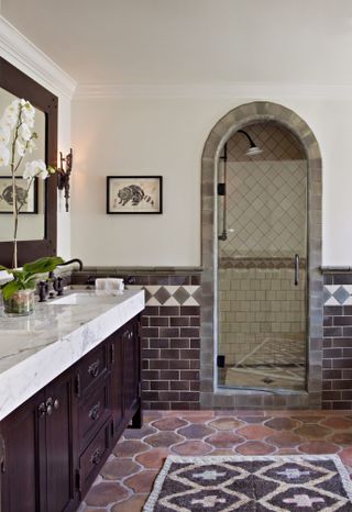 Bathroom with terracotta floor tiles, purple wall tiles and border