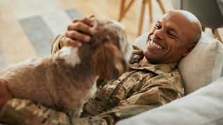 Smiling veteran lying on couch with his dog