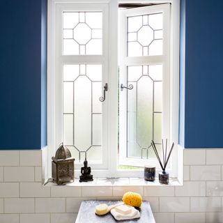 open bathroom window with navy blue painted wall and white tiles