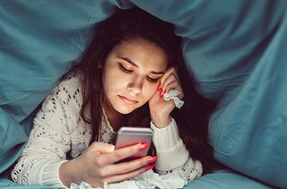 teen on phone under duvet