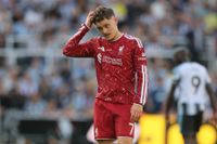 Florian Wirtz of Liverpool stood on the pitch, rubbing his head, looking dejected.