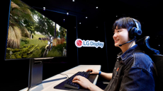 A young man playing a game in front of an LG RGB Tandem OLED gaming monitor