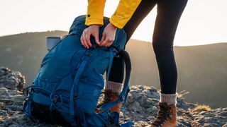 someone unzipping their hiking backpack out on the trail