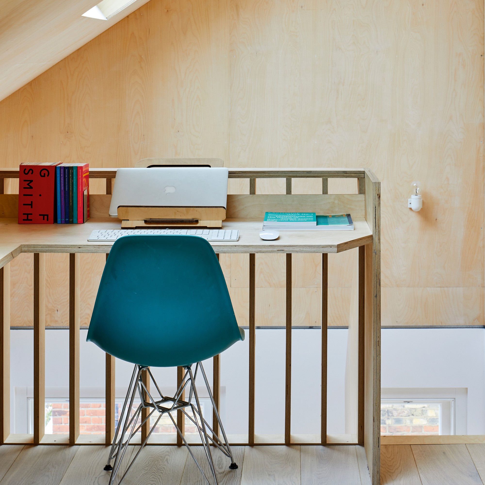 Home office with a built-in corner desk made from plywood with a laptop stand on top
