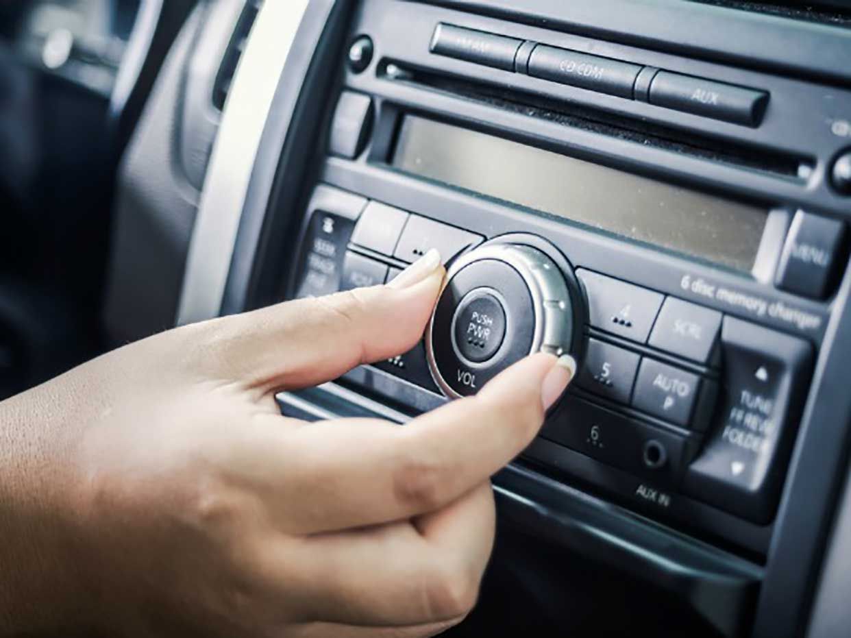 A hand turning a dial on a card radio