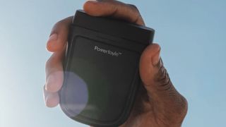A solar powered pair of earbuds held in a hand