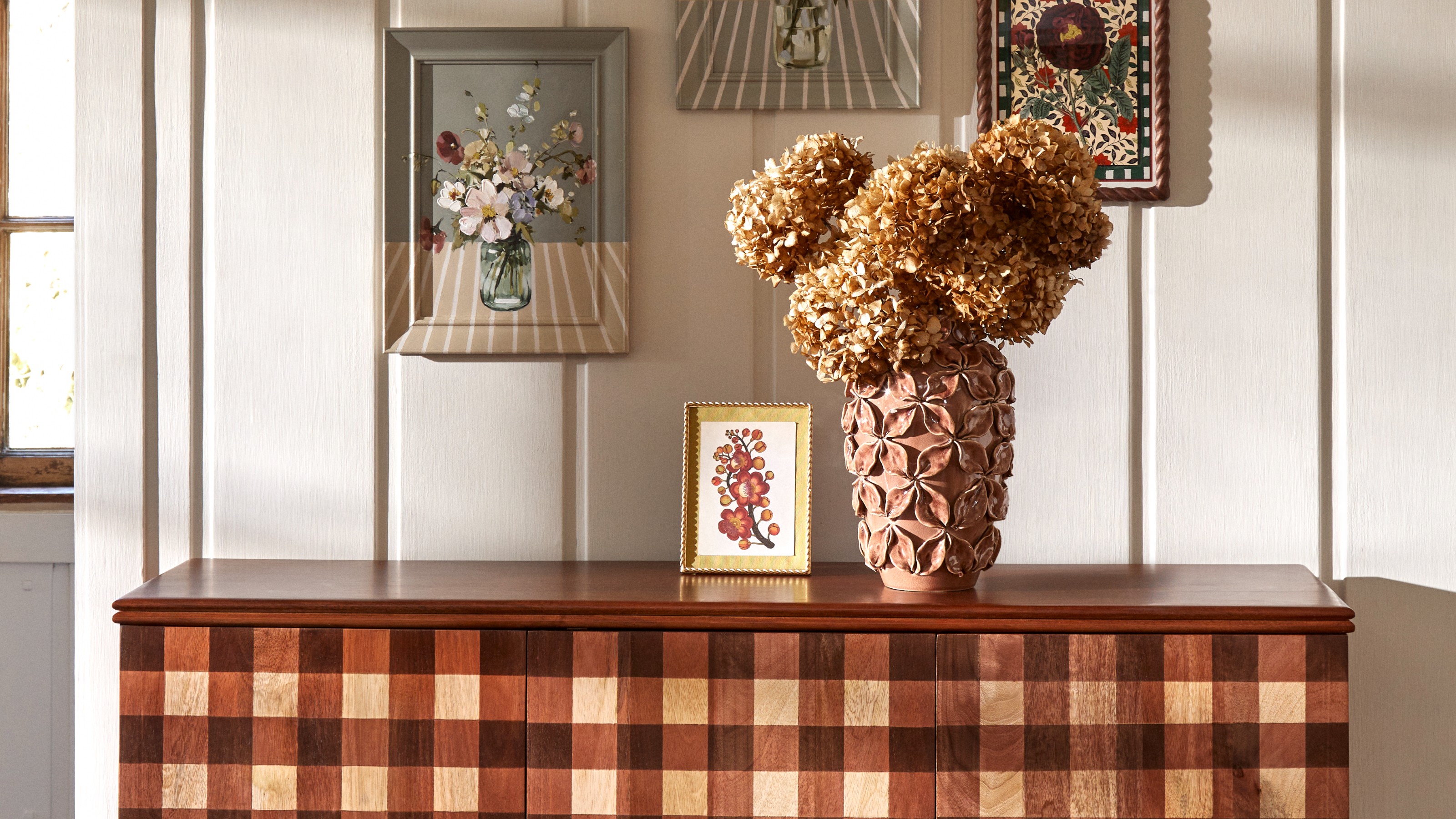 Dunelm Posie gingham sideboard against a panelled wall with a vase of dried hydrangeas on top and framed wall art above it
