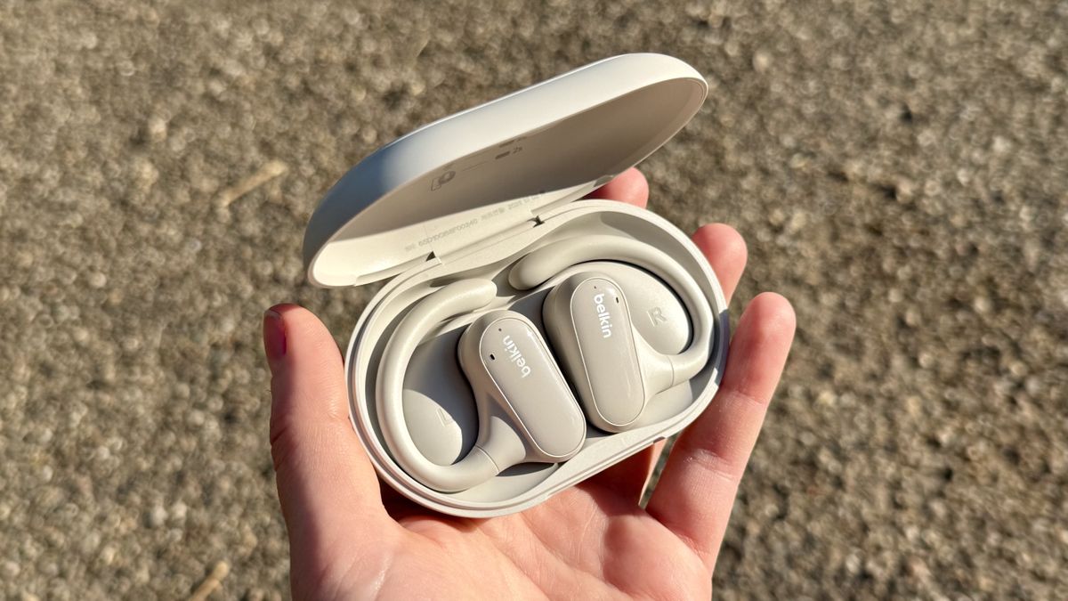 A hand holding the Belkin SoundForm Clear fit buds in their charging case.
