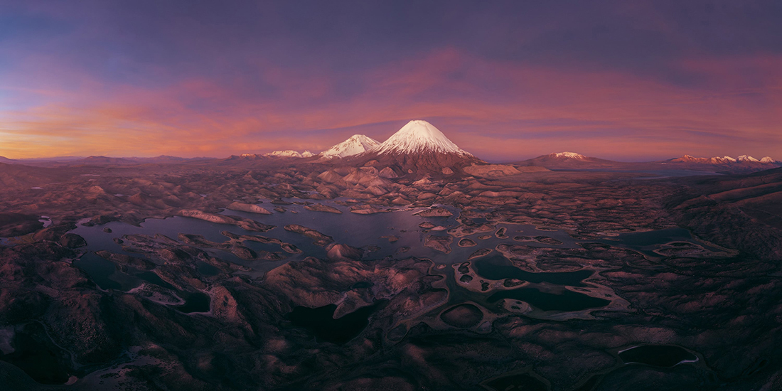 Captured in Chile, 'The Sleeping Giant' showcases Parinacota Volcano, neighbouring Pomerape and high-altitude lakes, all bathed in vivid hues as the sun sets, creating a spectacular panoramic landscape