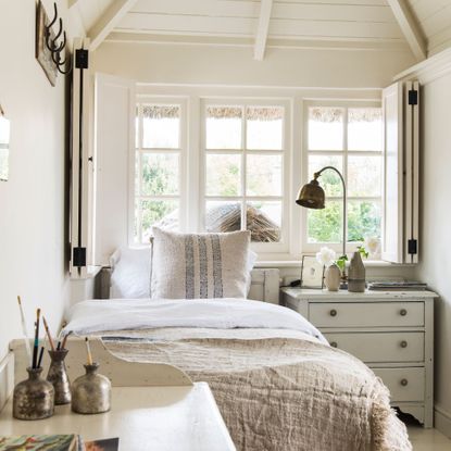 White spare room with single bed, chest of drawers and desk