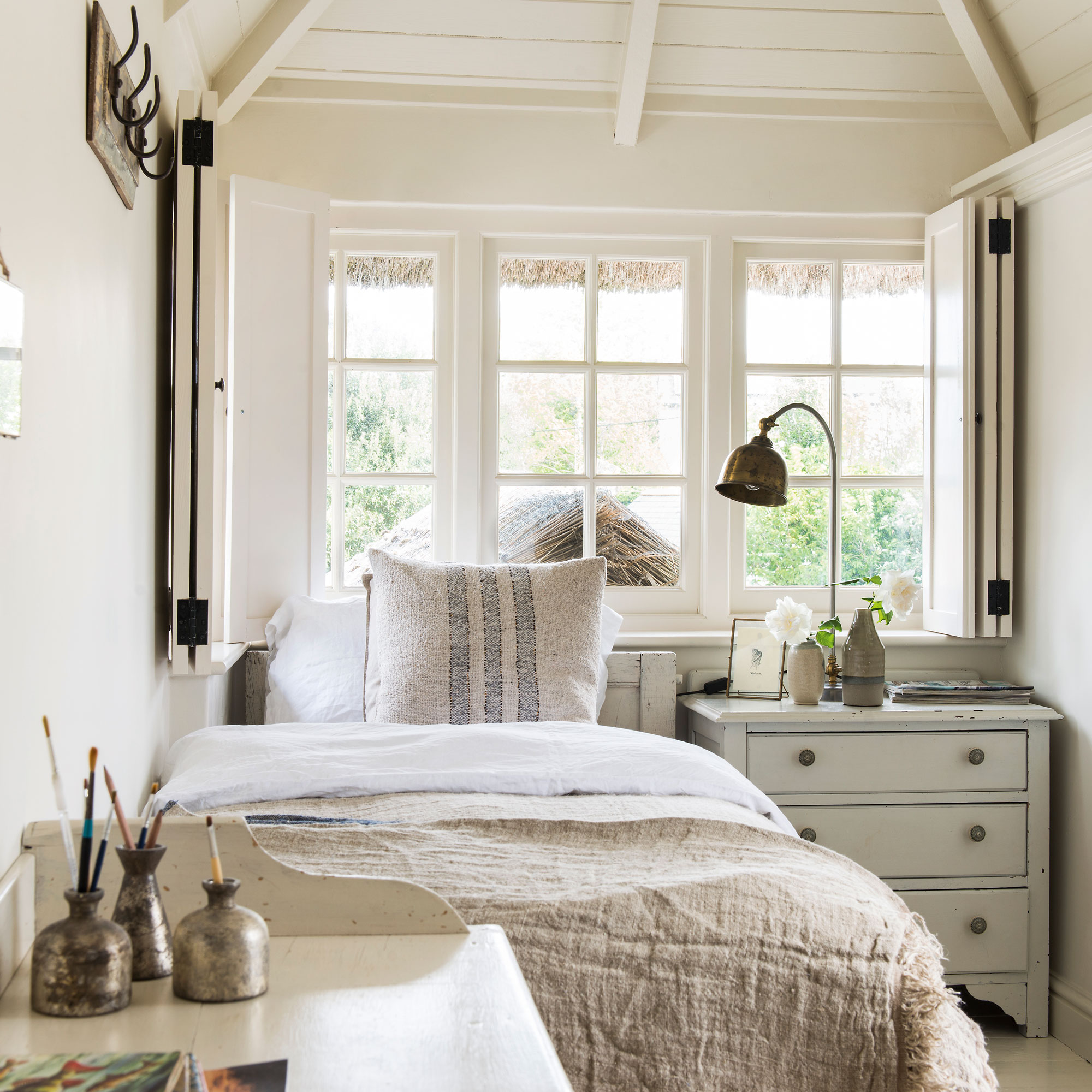 White spare room with single bed, chest of drawers and desk