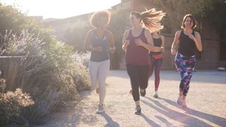 Women running together in a group down gravel path in the sunshine