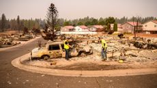 Utility workers help clear obstacles at a burned home during the Old Trails Fire in Spokane, Washington