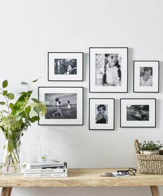 black and white family photos in a gallery wall above a wooden bench