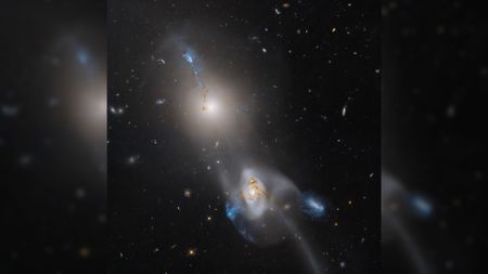 two colorful wisps of gas against thousands of background stars and galaxies