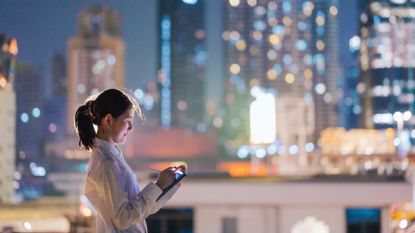 Woman working on a digital tablet in front of a blurry cityscape at night