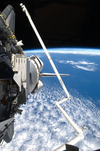 With a bright blue Earth in the background, the shuttle Discovery's robotic arm and heat shield inspection boom begins to conduct thorough inspections of the shuttle's thermal tile system on Feb. 25, 2011, flight day 2 of the shuttle's final spaceflight.