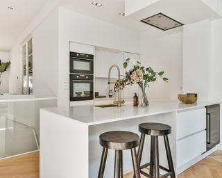 Small modern white kitchen white countertop and black barstools