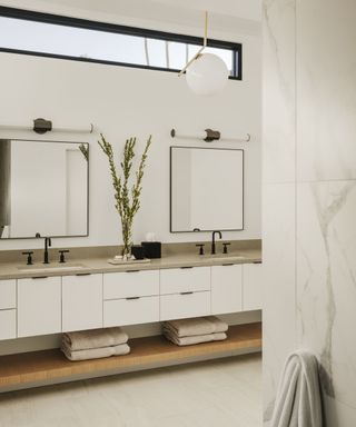White drawers, black framed window, twin mirrors and sinks
