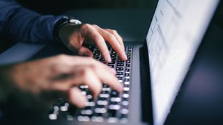 close-up of man typing on laptop