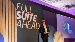 Evan Goldberg, founder and EVP, Oracle NetSuite standing in front of a sign that says 'FULL SUITE AHEAD' on a stage, lit by purple lighting