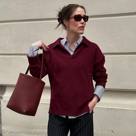Woman wears burgundy jumper, striped shirt, burgundy bag