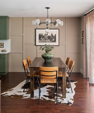 Wall paneling painted in stone, artwork, leather chairs, cowskin rug, retro lights, hint of kitchen