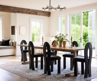 dining room with white walls and wooden beam and wooden table with black chairs