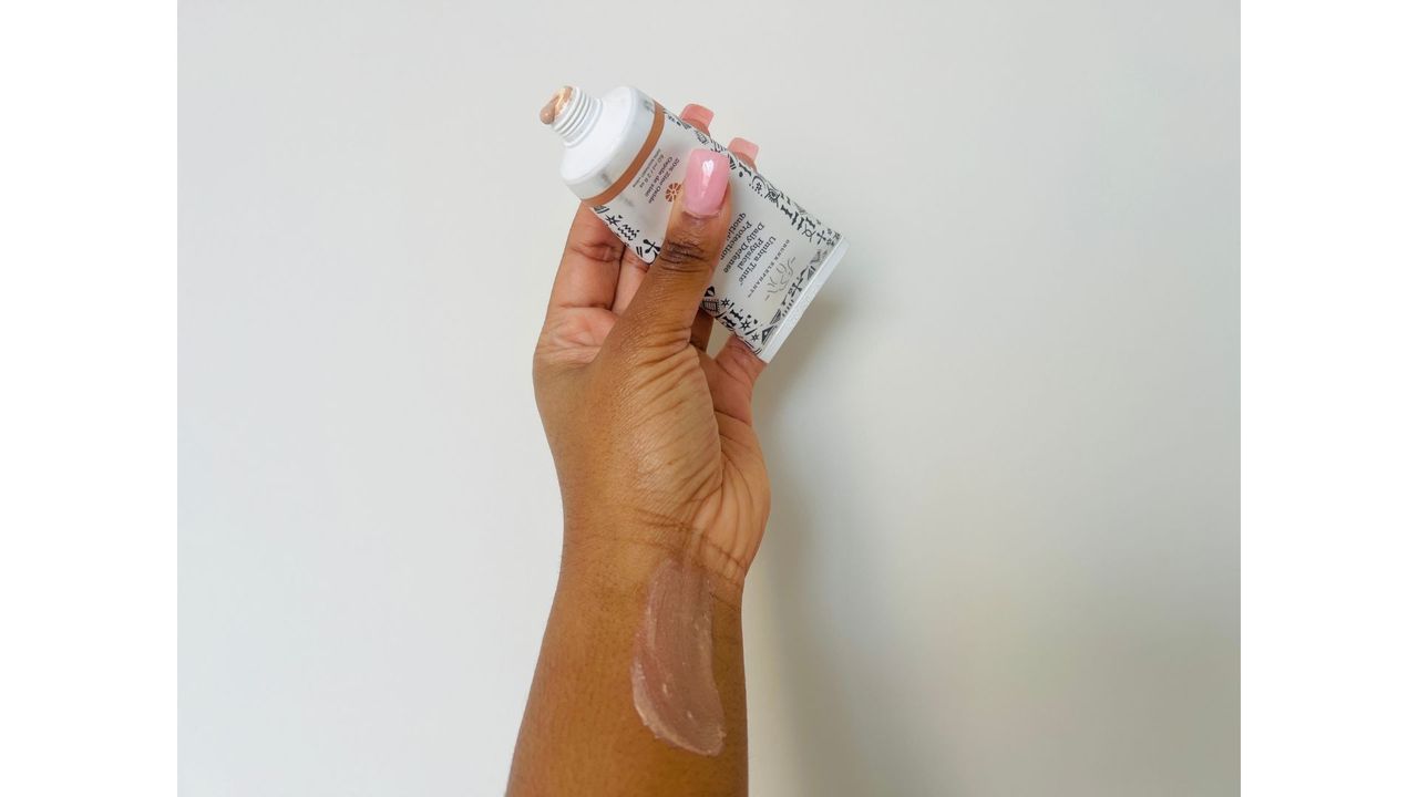 A person holding an opened Drunk Elephant Umbra Tinte squeeze tube for the best tinted moisturizer with SPF.