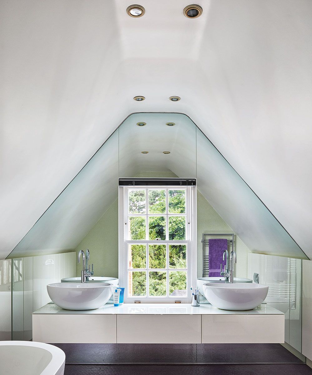 A large window in front of two sinks on a vanity unit with spotlights above