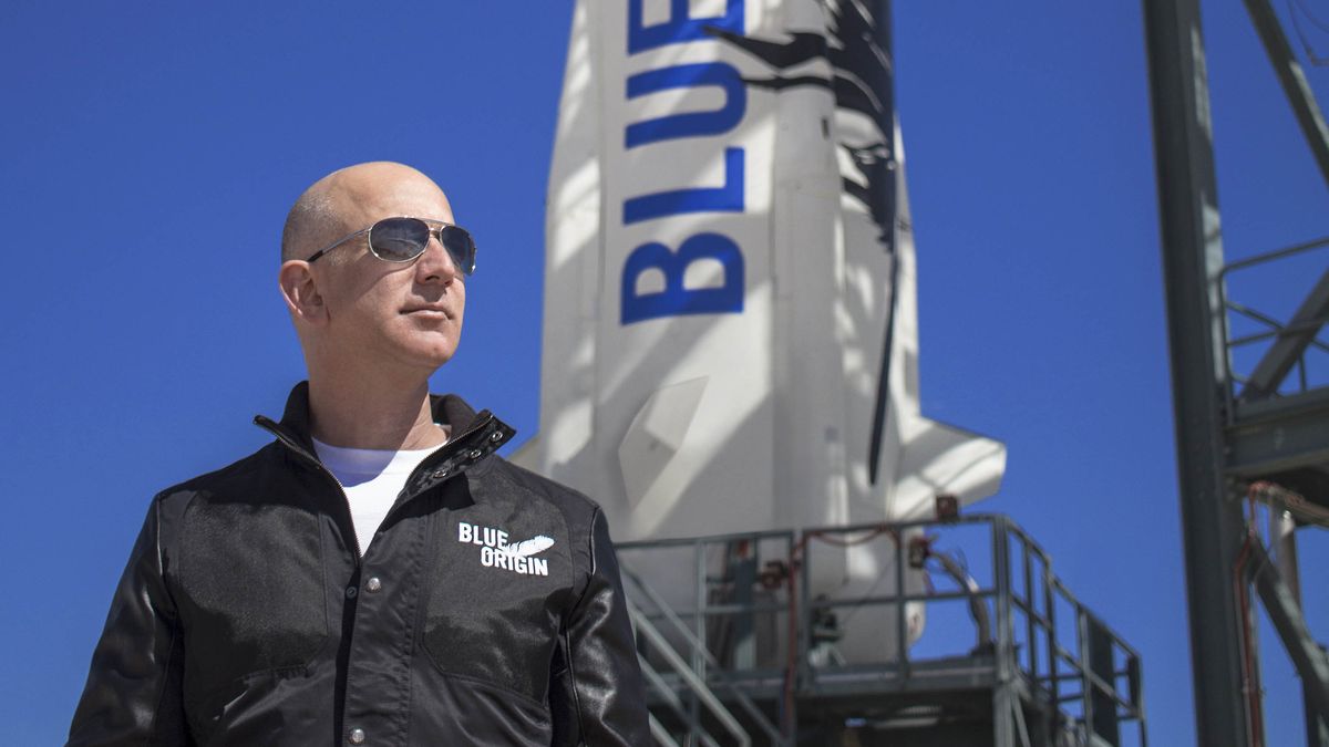 Jeff Bezos at the Blue Origin launch pad with a New Shepard rocket in the background.