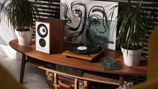 Mission 750 speakers on a table with a turntable, plants, and art