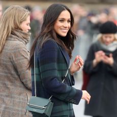Meghan Markle in a plaid coat and green crossbody bag