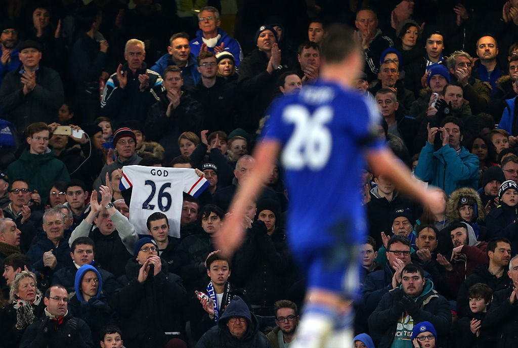 A fan holds up a shirt saying God and the number 26 as John Terry of Chelsea walks past during the Barclays Premier League match between Chelsea and Newcastle United at Stamford Bridge on February 13, 2016 in London, England.
