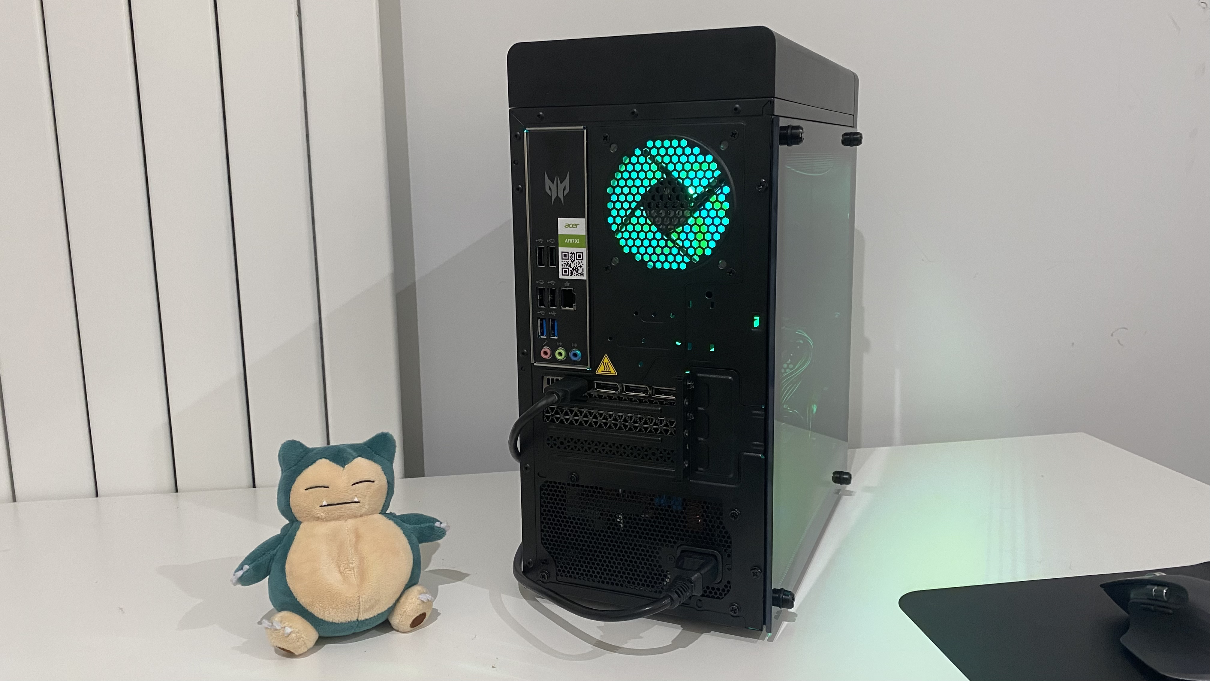 Acer Predator Orion 3000 desktop gaming PC shown from the rear. A Snorlax Pokemon plushie sits next to it.