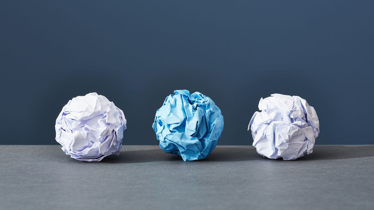 Three balled-up pieces of paper against a blue background.