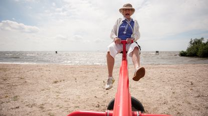 An older woman enjoys a seesaw on the beach on vacation.