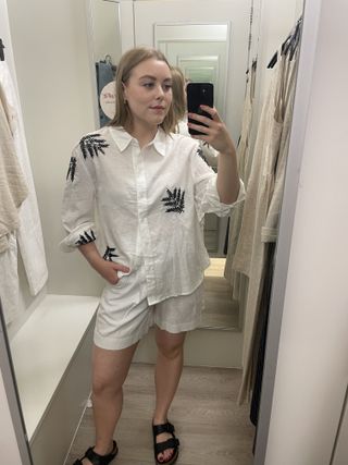 Woman in dressing room wears linen shirt and linen shorts