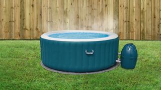 Inflatable hot tub in a backyard with green grass and wood fence