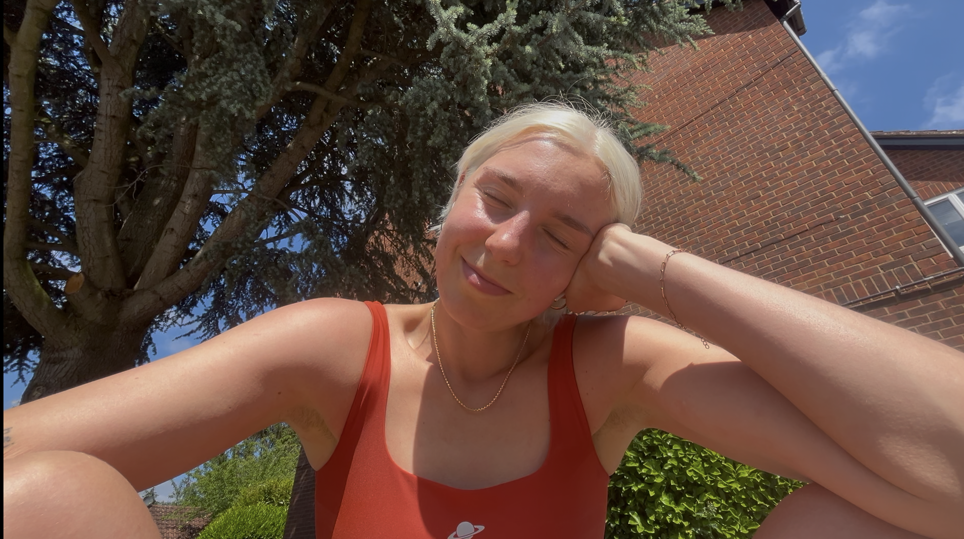 A woman taking a selfie with her eyes closed in the sunshine after a walk