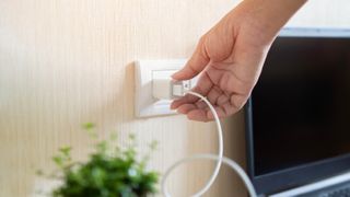 Woman unplugging from socket wall