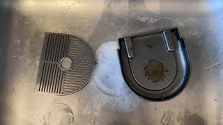Removable trays from Keurig machines being washed in basin