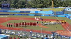 The Japan and Australia women’s softball teams line up ahead of the opening match at Tokyo 2020 