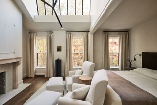 The primary suite bedroom, featuring tall ceilings with large windows and neutral bedding